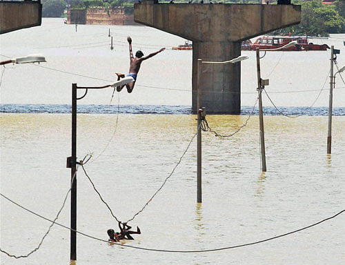 A boy jumps from submerged electric poll in the flooded water of river Ganga in Allahabad on Sunday. PTI Photo