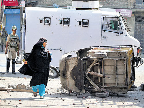 aftermath: A woman walks past an overturned auto rickshaw after a night of clashes  between protesters and security forces in Srinagar. REUTERS