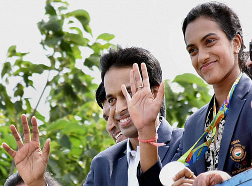 Olympic Silver Medalist P.V.Sindhu with her Coach Gopi Chand greets well wishers after her arrival at Rajiv Gandhi International Airport in Hyderabad on Monday. PTI Photo