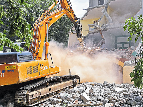 An ashram being razed for encroaching upon the rajakaluve at Halagevaderahalli, in Rajarajeshwari Nagar, on Tuesday. dh Photo