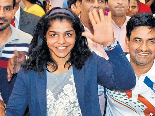 Rio Olympics bronze medallist Sakshi Malik waves to her fans as she arrives at New Delhi airport on Wednesday. PTI