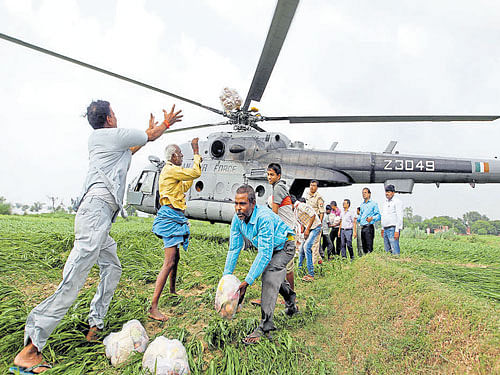 Food parcels are unloaded from an IAF helicopter to be distributed among those affected by floods on the outskirts of  Allahabad on Thursday. Reuters Photo.