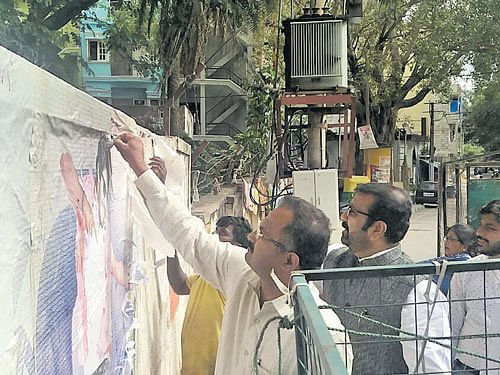 Mayor B N Manjunath Reddy pulls downa poster on Richmond Road as part of the campaign.