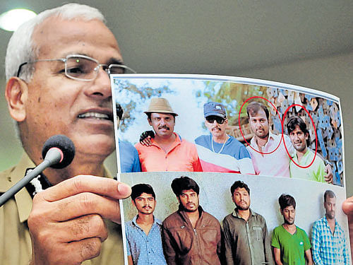 Police Commissioner NS Megharikh shows the photo of the five suspects at a press conference in the city on Monday. The faces of the two prime suspects, Muniyappa and Hasan Dongri, have been circled. DH PHOTO