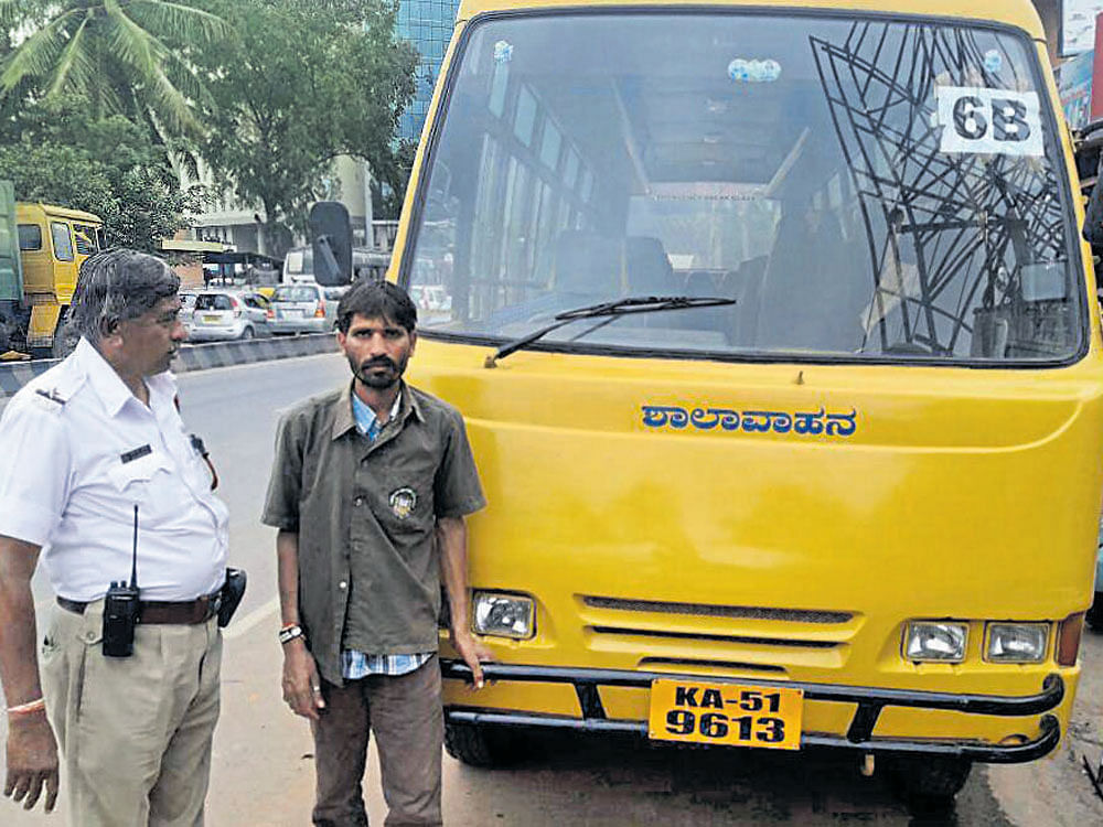 A traffic cop questions Ananda, bus driver with Narayana Techno School in Yelahanka, who was held for drunk-driving on Wednesday. DH photo