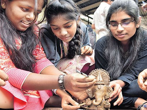 Students prepare Ganesha idols at a programmeorganised to promote an eco-friendly Genesha festival at the Government College grounds in Malleswaramon Thursday. DH PHOTO