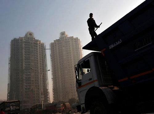 A labourer stands on a truck carrying construction materials at a construction site of residential buildings in Noida on the outskirts of New Delhi November 29, 2013. REUTERS