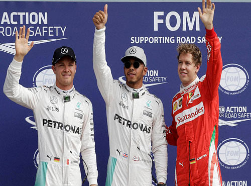 Mercedes driver Lewis Hamilton, of Britain, center, celebrates after setting the fastest time with second placed Mercedes driver Nico Rosberg, of Germany, left, and third placed Ferrari driver Sebastian Vettel, of Germany, after the qualifying session for Sunday's Italian Formula One Grand Prix at the Monza racetrack, Italy, Saturday, Sept. 3, 2016. AP/PTI