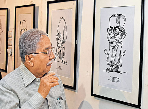 Writer Chandrashekhara Kambara looks at a caricature depicting him drawn by Nirmish Thaker at the exhibition 'Jnanapith Awardees in Caricatures' organised by the Indian Institute of Cartoonists at the Indian Cartoon Gallery in Bengaluru on Saturday. DH PHOTO
