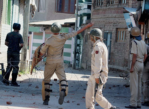 A policeman throws stones on protesters during clashes which erupted after police disrupted a protest rally, at Waniyar in Srinagar on Sunday. PTI Photo