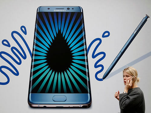 A woman speaks on an phone as she passes an advert for the Samsung Galaxy Note 7 in London. Reuters Photo.