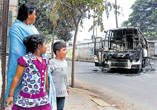 A woman and her children look at a burnt bus at Timber Yard Layout. DH Photo
