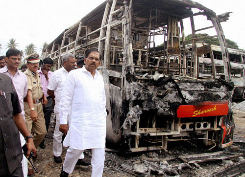 Karnataka Home Minister G Parameshwar with top police officials visiting KPN Depot Buses which were torched by the protesters on Cauvery issue near Mysore Road in Bengaluru on Wednesday. PTI Photo
