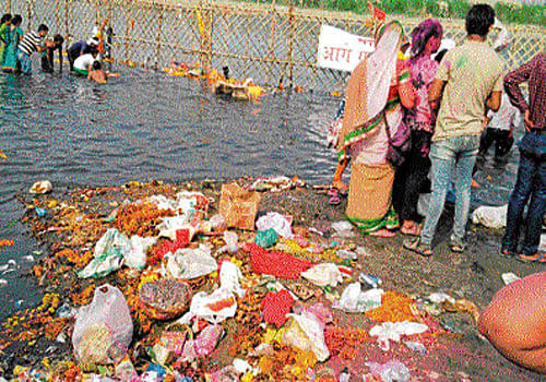 Puja materials like flowers and oil are strewn on the Yamuna Ghat after the immersion of idols of Ganesh on Thursday.  DH