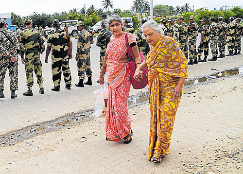 Passengers cross over to Karnataka on foot as the bandh in Tamil Nadu affects the movement of vehicles on the inter-state border at Attibele in Bengaluru on Friday. Border Security Force personnel guard the area. dh PHOTO / Kishor Kumar Bolar