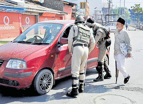 Security personnel stop a car for an elderly handicapped man during the curfew, at Jehangir Chowk in Srinagar, on Friday. PTI