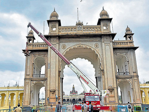 Electricians replace old incandescent light bulbs with new ones at Jayamarthanda Gate  of Mysuru Palace, on Friday. Dh photo