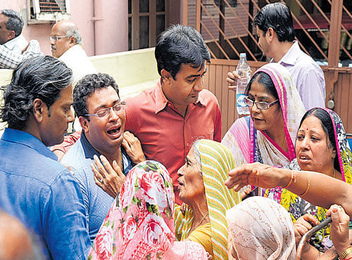 Relatives and family friends mourn in front of the house where Santhoshi Bai and Latawere murdered on Millers Road, Vasanthnagar on Monday. DH PHOTO