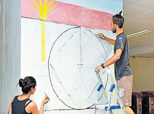 Students of Srishti School of Art and Design paint a mural at Cubbon Park Metro station on Monday, as part of Art in Transit project. DH PHOTO