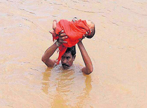 A father holds aloft his sick daughter as he crosses an overflowing stream in Kudumusari village of Visakhapatnam district in Andhra Pradesh on Tuesday. Heavy rain over the last week saw the streams well, cutting off all connectivity. After Pangi Sathibabu reached the banks, he trekked another 5km to reach the main road and then the health centre.