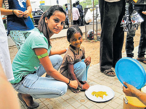 A volunteer of Feeding India serves food to an underprivileged child. A boy enjoys nutritious food. courtesy Feeding India