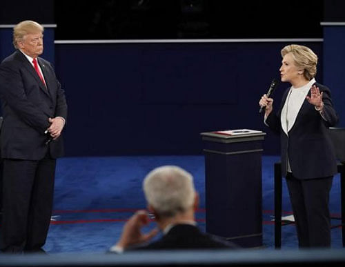 Democratic U.S. presidential nominee Hillary Clinton speaks as Republican U.S. presidential nominee Donald Trump looks on during their presidential town hall debate at Washington University in St. Louis, Missouri, U.S.  REUTERS