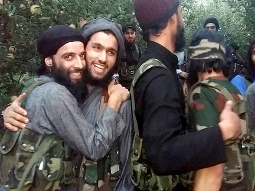 Hizbul Mujahideen Militants greets eachother while displaying weapons which they snatched from police personnel in various attacks, at an apple field in South Kashmir on Wednesday. PTI Photo