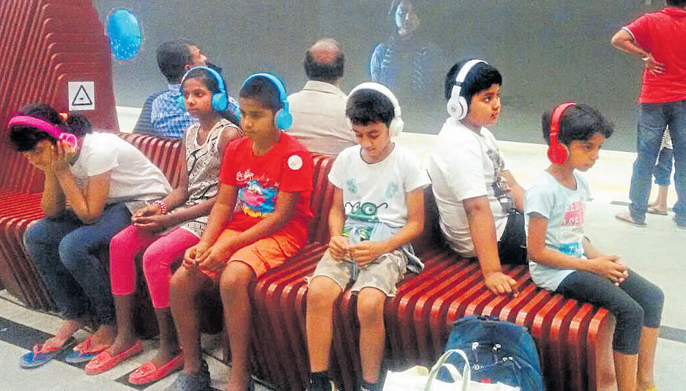 engrossed A group of children listening to the audio installation 'In Transit' at Cubbon Park Metro Station.
