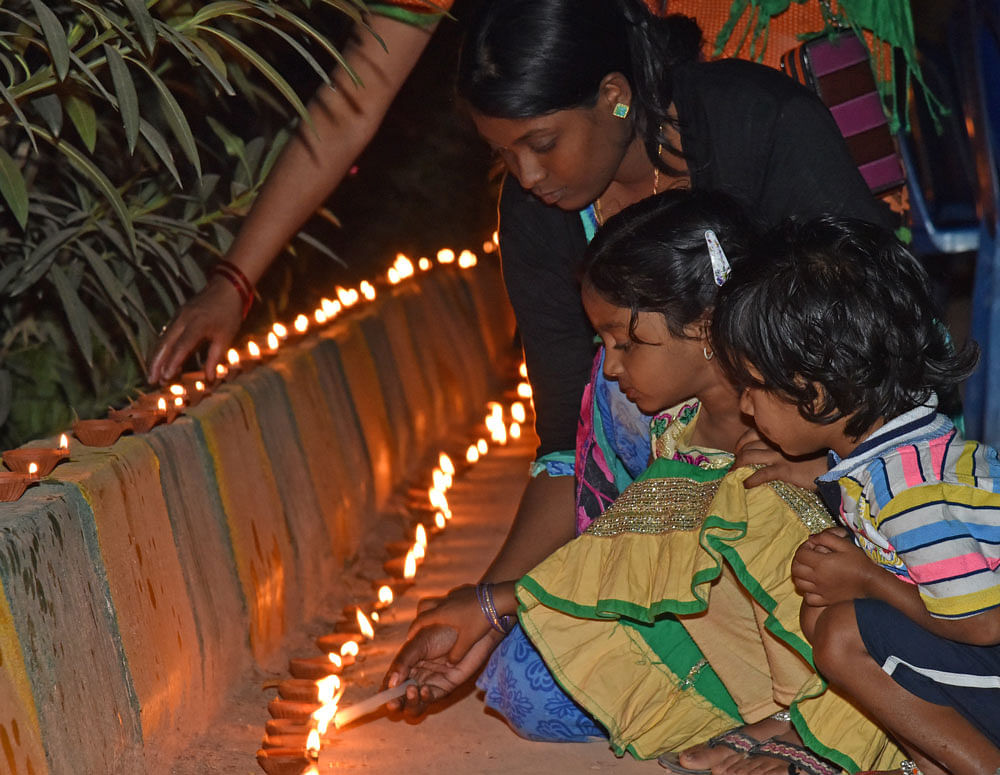 Women and children light lamps at Kere Deepotsava, an eco-friendly celebration of Deepavali jointly organised by United Way, K R Puram Kere Mattu Parisara Samrakshana Trust and BBMP at Kaudenahalli Lake on Wednesday. DH photo