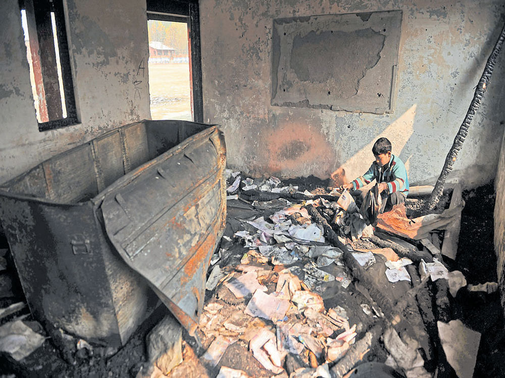 Pause in learning: A student sits among rubble at a partially burnt government high school in Goripora on the outskirts of Srinagar on Wednesday. AFP
