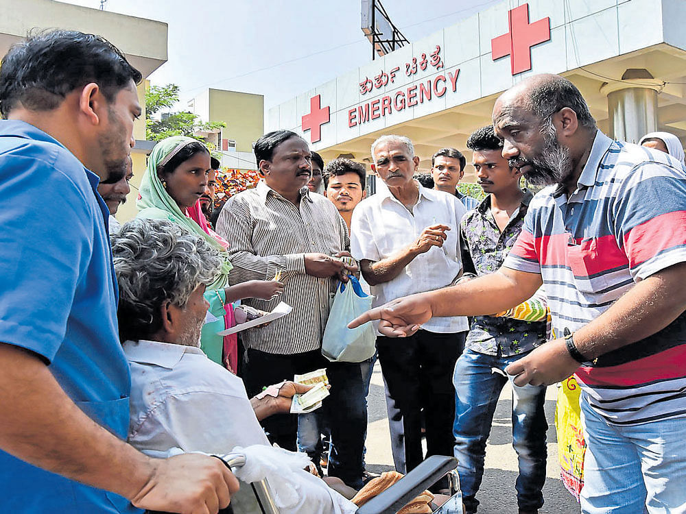 International kite flier V Krishnoji Rao (extreme right) and his friends distribute Rs 100 notes to patients in exchange for Rs 500 currency at Bowring Hospital on Sunday. DH Photo