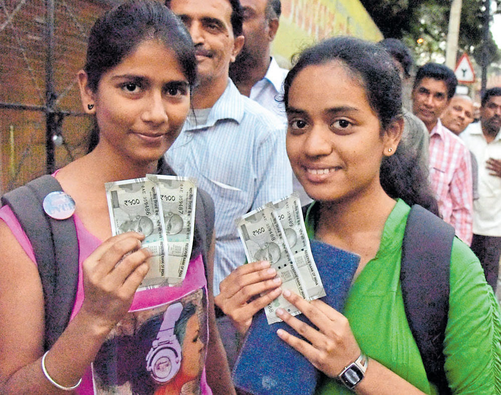 Girls show the new Rs 500 notes after withdrawing them from an ATM of the State Bank  of Mysore on Avenue Road on Monday.  dh photo