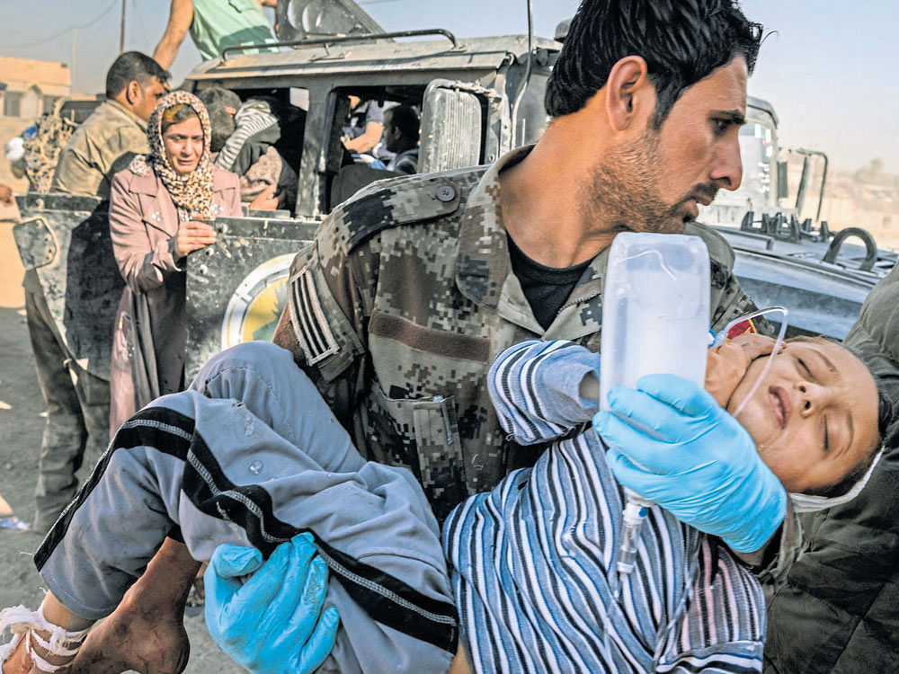 collateral damage: A medic carries a child wounded during fighting to a field hospital on the outskirts of Mosul. An Iraqi govt order  imploring civilians to stay in their homes while the battle to regain the city raged, has cost them dearly. NYT