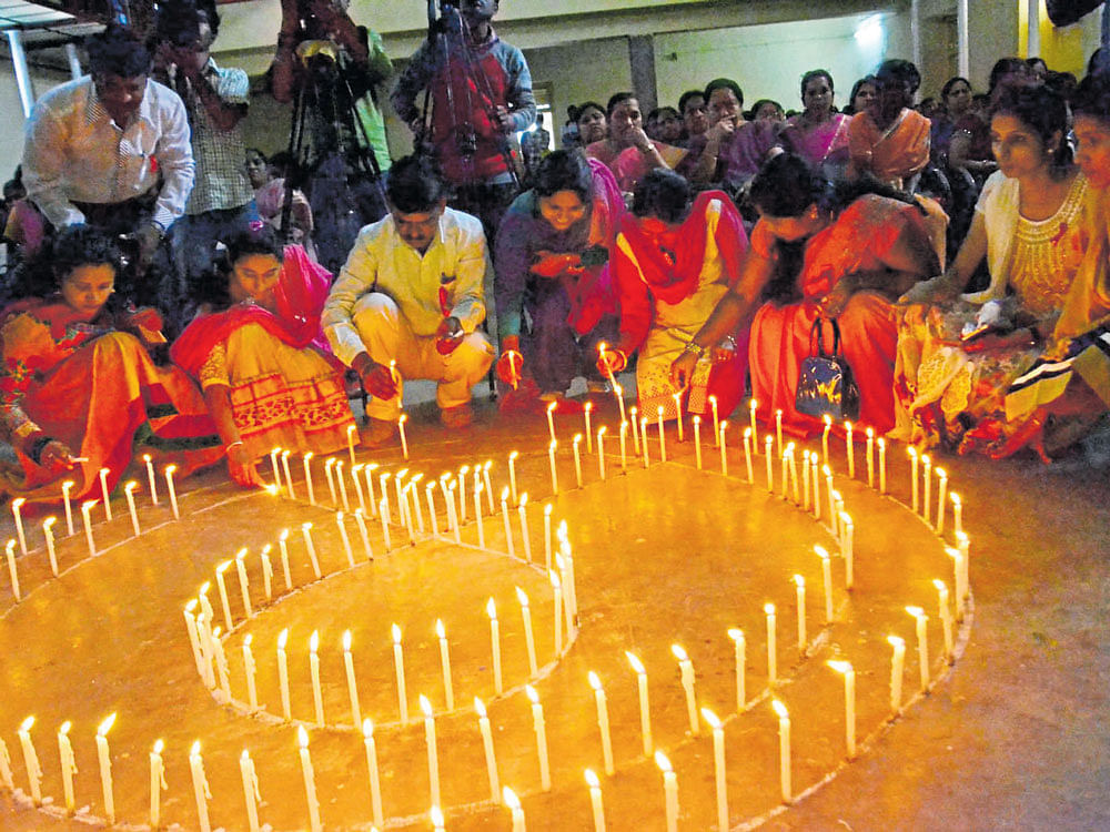 People light candles arranged in the form of a red ribbon (symbol of awareness against various abuses and expressing solidarity with HIV infected  people), as part of World AIDS&#8200;Day in Madikeri on Thursday. DH photo