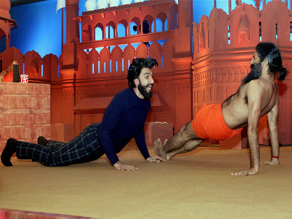 Bollywood actor Ranveer Singh performs yoga with Swami Ramdev at Agenda Aaj Tak 2016 Summit in New Delhi on Tuesday. PTI Photo