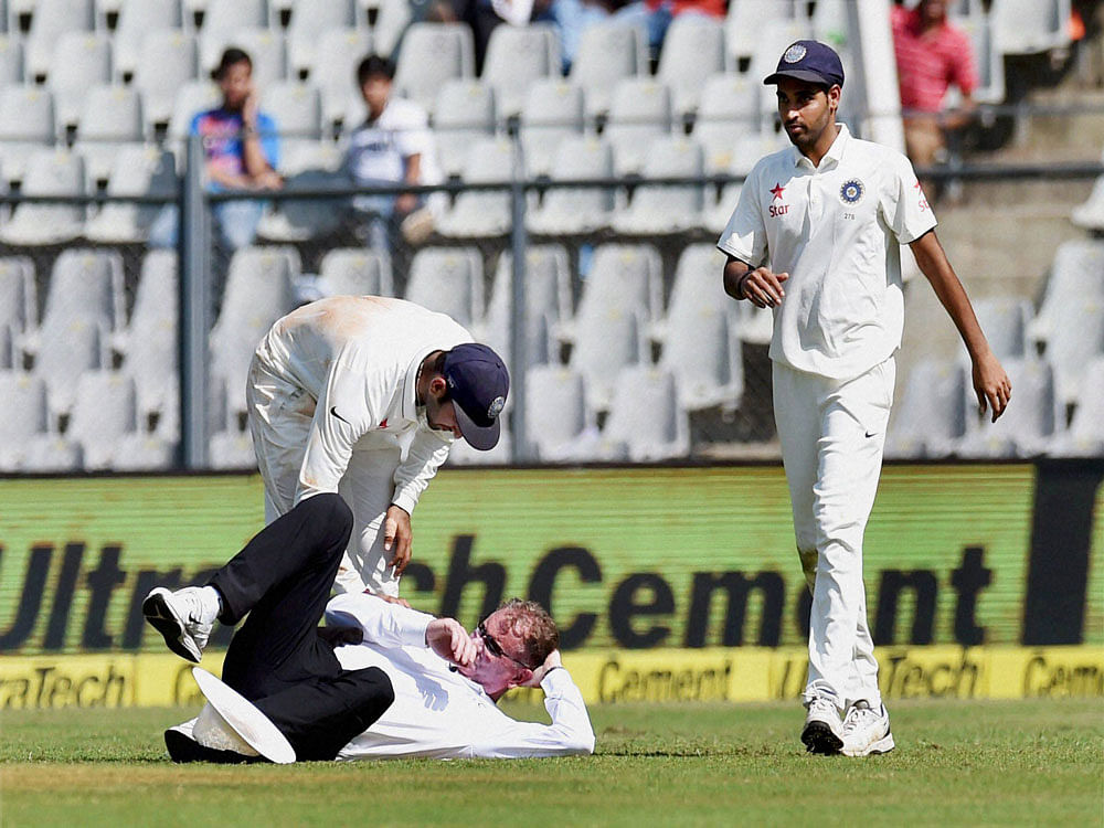 India's Cheteshwar Pujara helps the Umpire, Paul Reiffel after he fell down during the first day of the fourth Test match between India and England in Mumbai on Thursday. PTI Photo