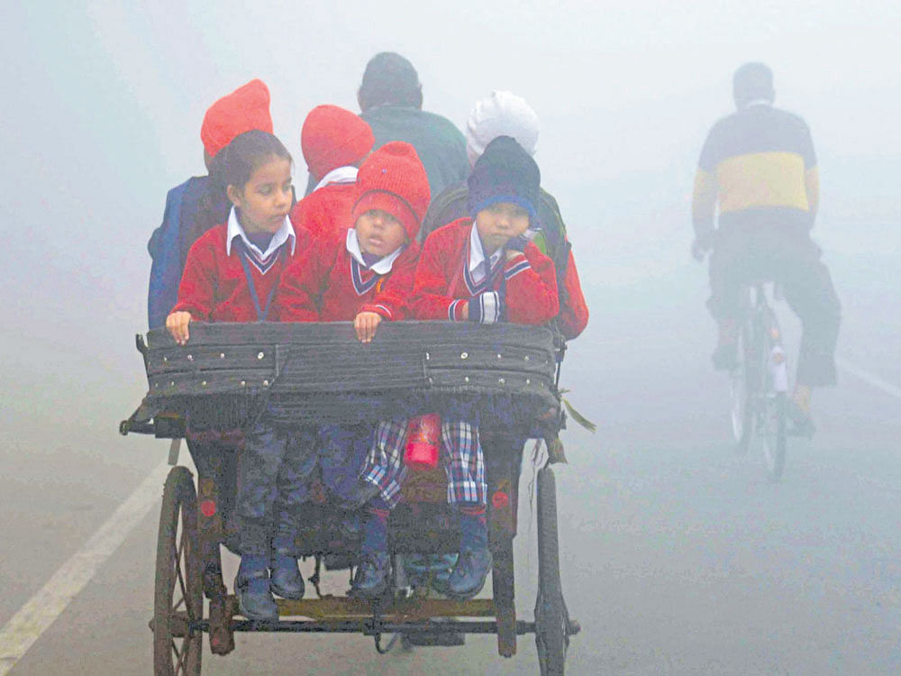 EARLY MORNING BLUES: Children travel by a rickshaw to school on a cold and foggy morning in Amritsar on Thursday.