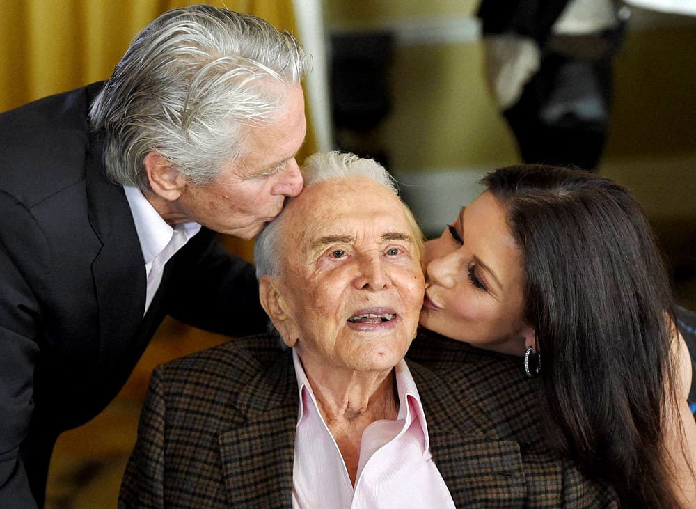 ctor Kirk Douglas, center, gets a kiss from his son Michael Douglas, left, and Michael's wife Catherine Zeta-Jones during his 100th birthday party at the Beverly Hills Hotel on Friday. AP/PTI