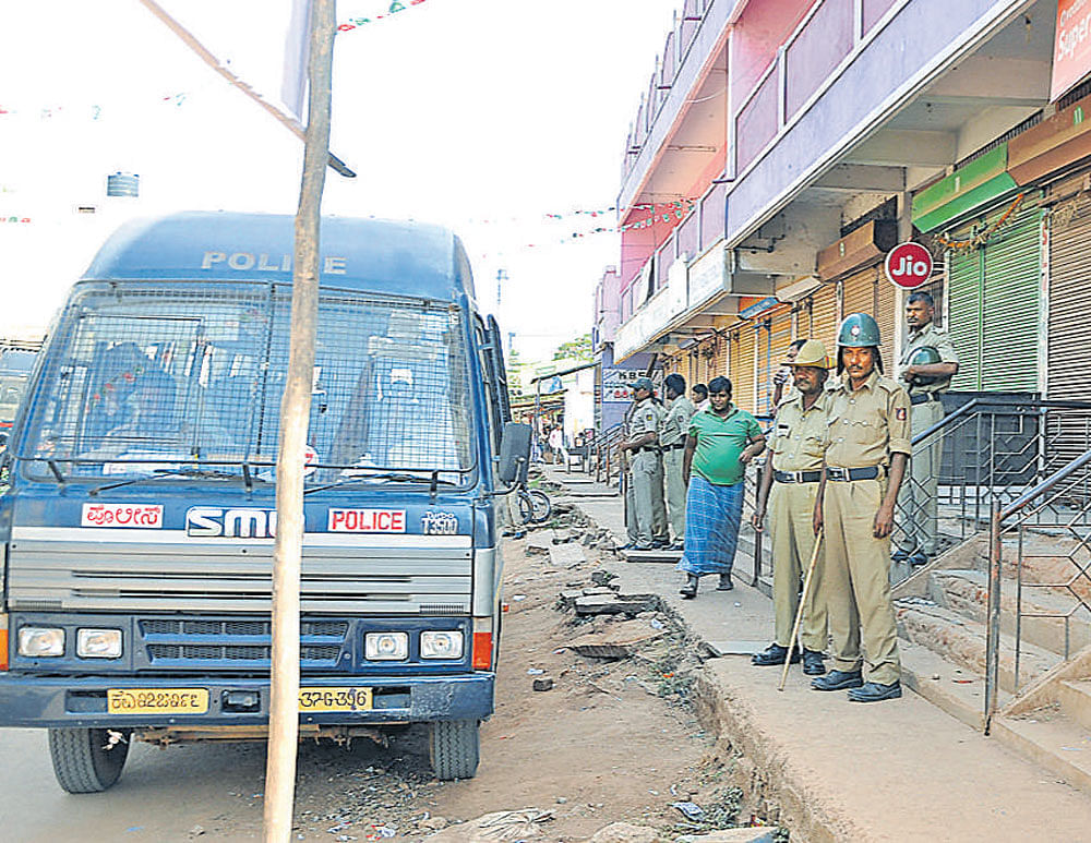 Police keep a vigil as shops remain closed following a communal clash at Hosapete in Ballari district on Monday. dh photo