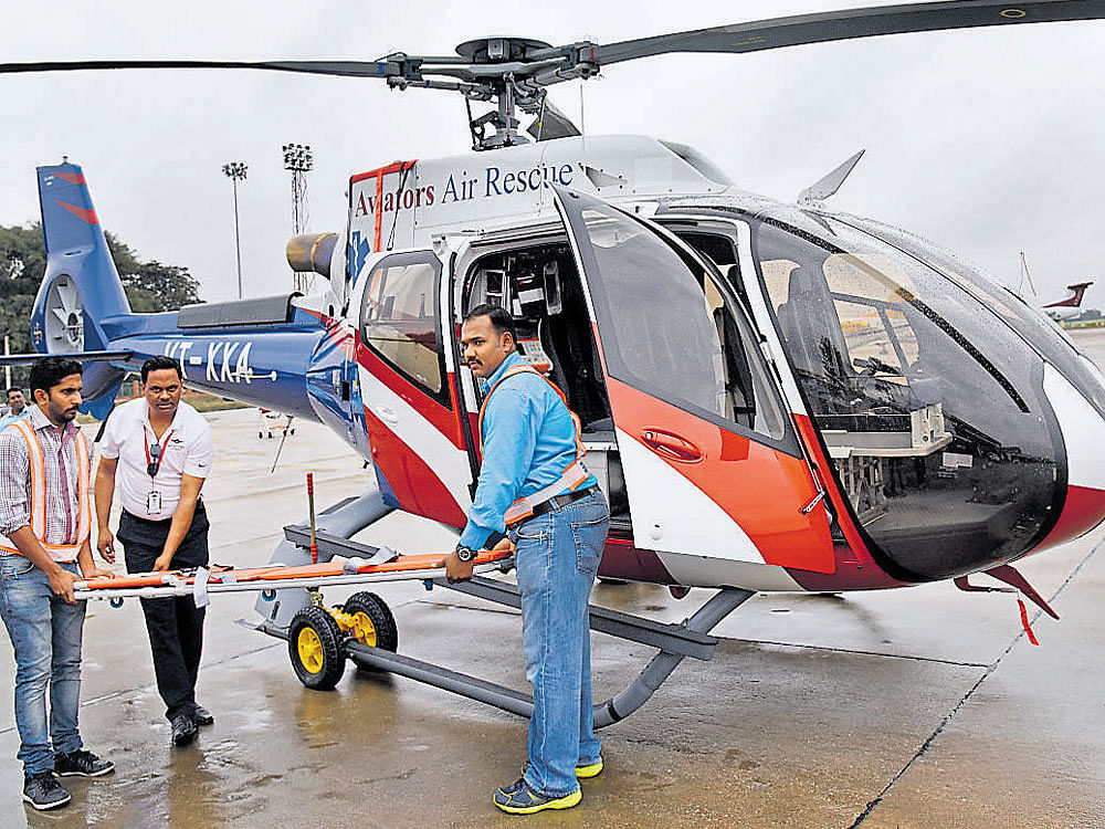 Aviator Air Rescue Executive Pilot Capt Amitabh Dey (centre) shows the stretcher and other facilities on the country's first dedicated air ambulance service after the launch at the HAL airport in Bengaluru on Friday. DH Photo