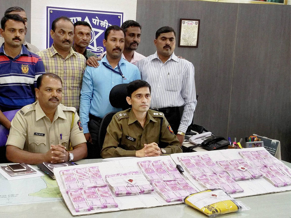Senior police officer Sandeep Patil showing the new currency notes worth Rs 60 Lakhs seized from exchangers at Bombay Restaurant Chowk, in Satara, Maharashtra on Tuesday. PTI Photo