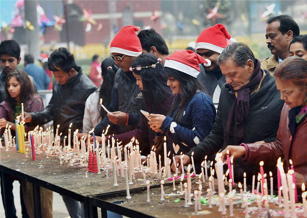 People light candles at Sacred Heart Cathedral on the Christmas festival in New Delhi on Sunday. PTI Photo