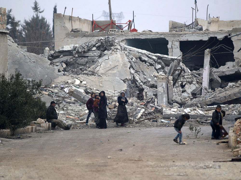 People stand near near rubble of damaged buildings in al-Rai town, northern Aleppo countryside, Syria December 25, 2016. REUTERS Photo