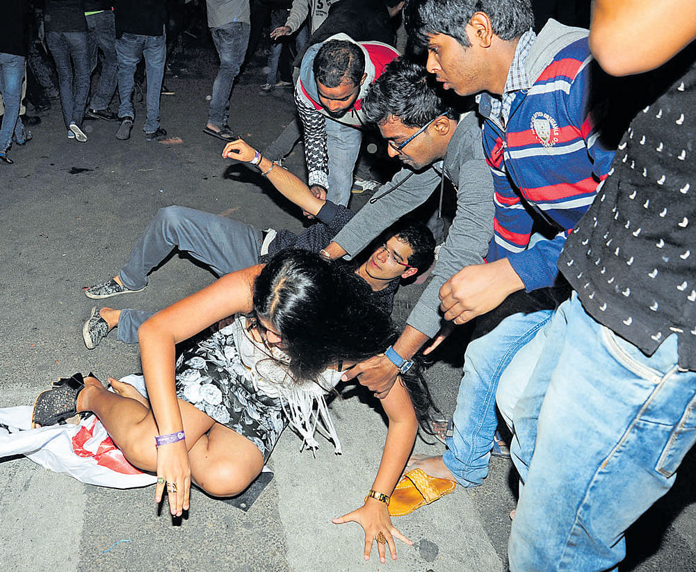 A group of youth helps a woman reveller who tripped on Brigade Road on New Year's Eve. DH&#8200;Photo / Ranju P