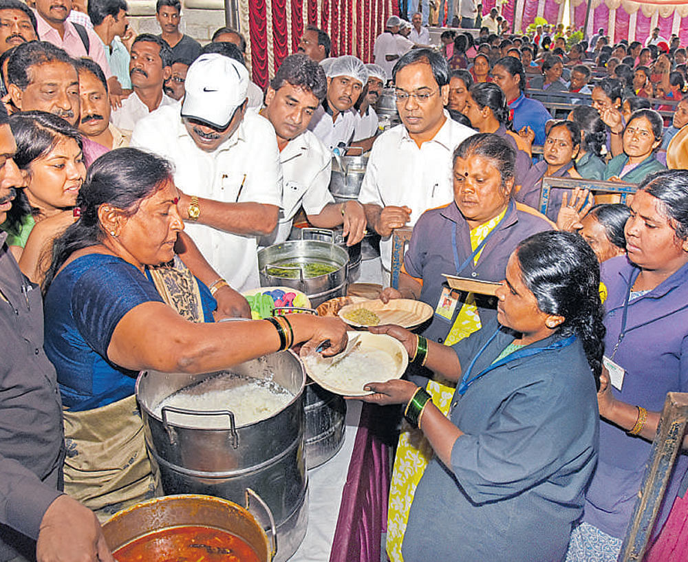 Mayor G Padmavathi serves food to pourakarmikas after  inaugurating the midday meal scheme for the BBMP south  division at Town Hall on Monday. dh photo