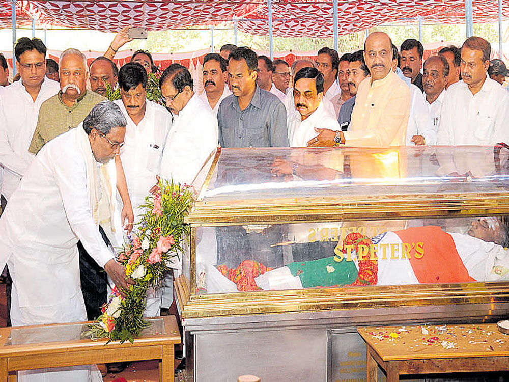 Chief Minister Siddaramaiah pays floral tributes to Cooperation and Sugar Minister H S Mahadeva Prasad at a ground in Halahalli, Gundlupet taluk, Chamarajanagar district, on Wednesday. Home Minister G Parameshwara and Public Works Minister Dr H C Mahadevappa look on. DH PHOTO