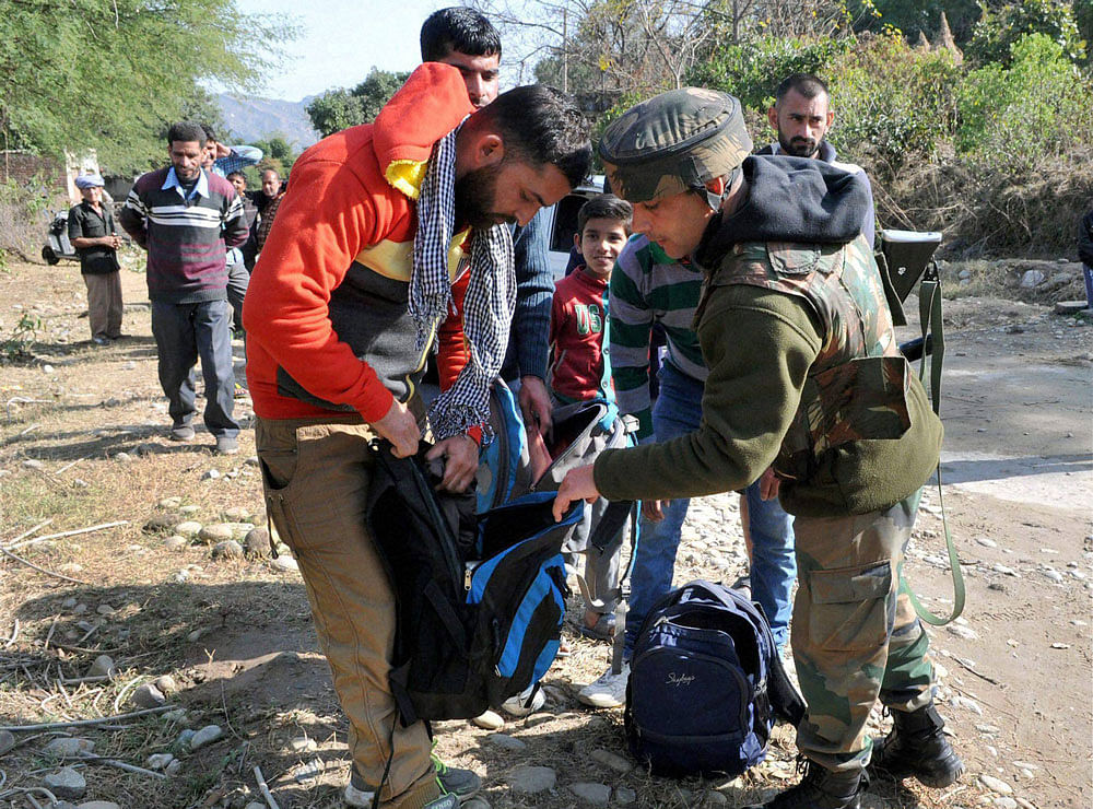 Army soldiers frisk bags of civilian during a search operation outside the camp of the General Engineering Reserve Force (GREF), the site of a militant attack, in the frontier Battal area, about 90 kms from Jammu on Monday. PTI Photo