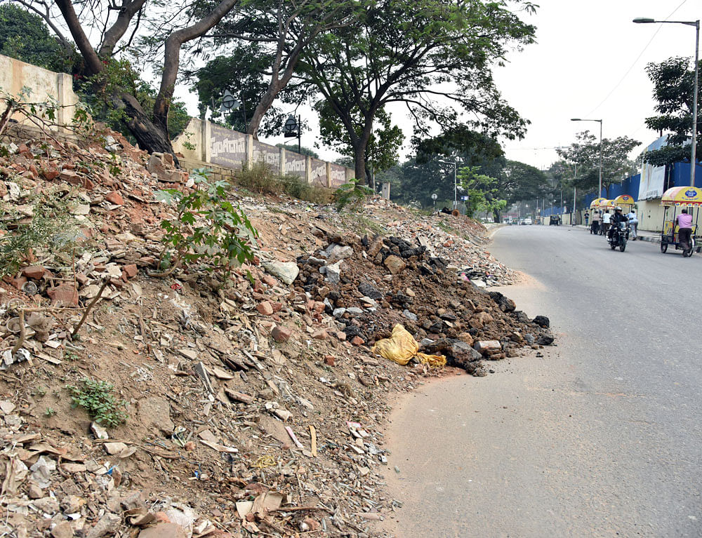 Debris dumped on the footpath on the Okalipuram main  road on Wednesday. DH photo