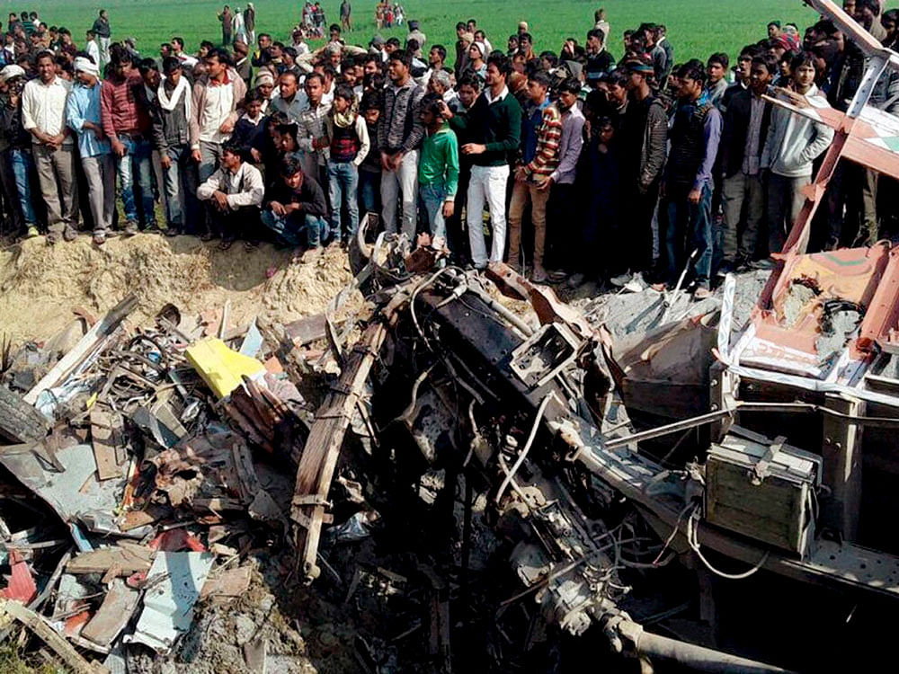 People examine the  mangled remains of the vehicles on the Aliganj-Paliyali Road in Etah district on Thursday. PTI