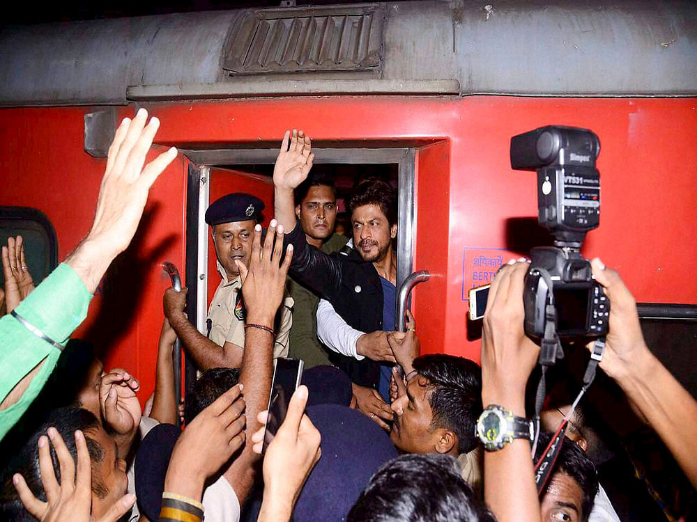 Actor Shah Rukh Khan waves to fans as he travels from Mumbai to Delhi in August Kranti Rajdhani Express while promoting his upcoming film Raees, during his stopover in Vadodara on Monday night. PTI Photo